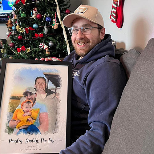 A man by a Christmas tree holding a framed family portrait